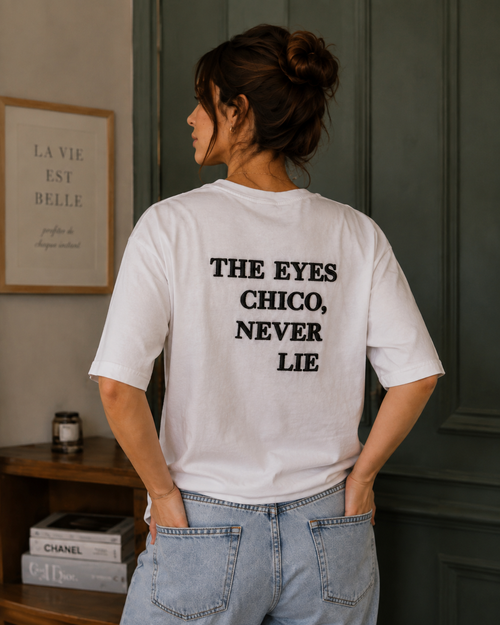 Back view of model wearing Queenly Eyes Never Lie white regular-fit T-shirt with black puff-print text