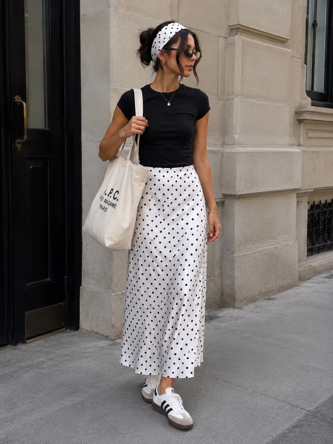 Ivory polka dot satin maxi skirt styled casually with headband, tote bag and sneakers