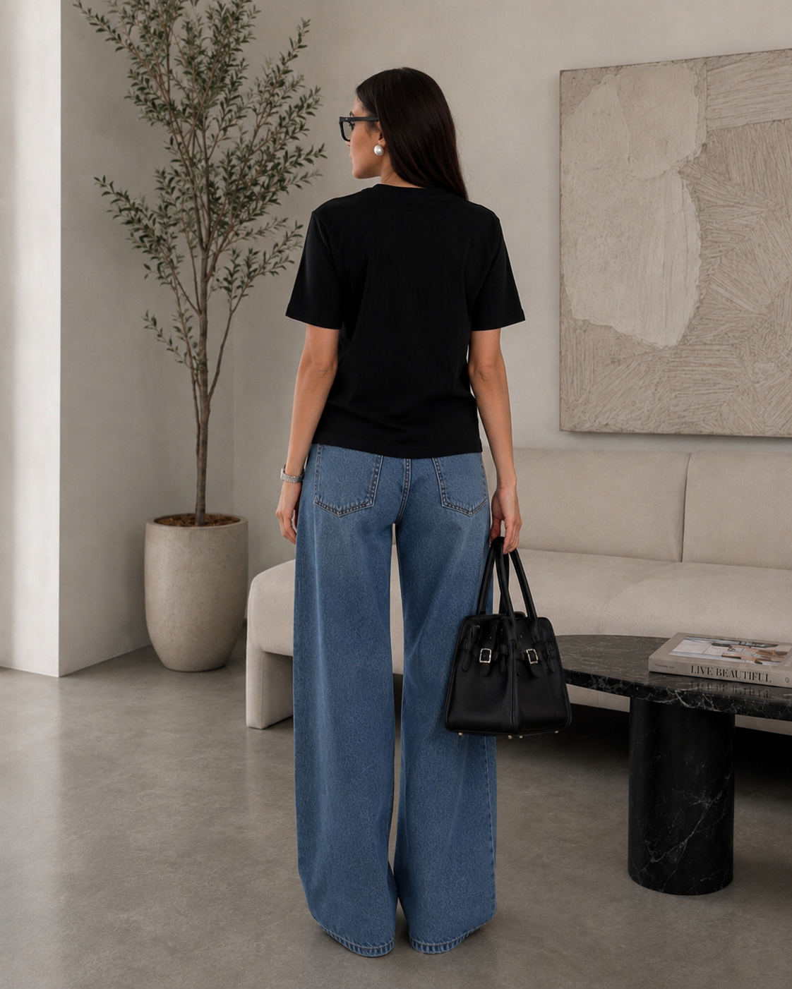 Back view of woman wearing the Queenly Mon Chéri black regular-fit tee with blue wide-leg denim