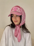 Woman styling a pink embellished cap with matching printed scarf